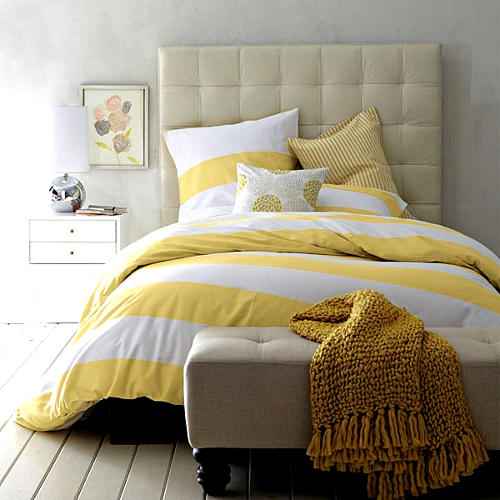 Banco longo nos pÃ©s da cama em tons amarelo